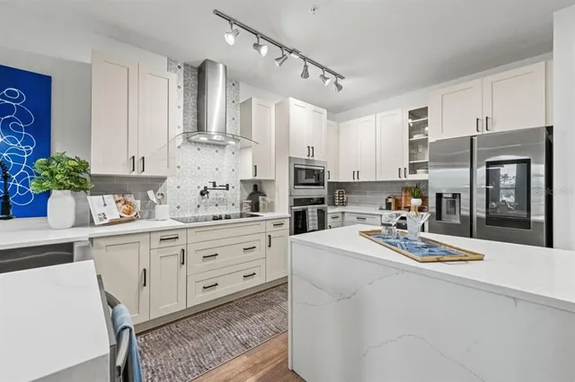 a kitchen with stainless steel appliances kitchen island a refrigerator sink and cabinets