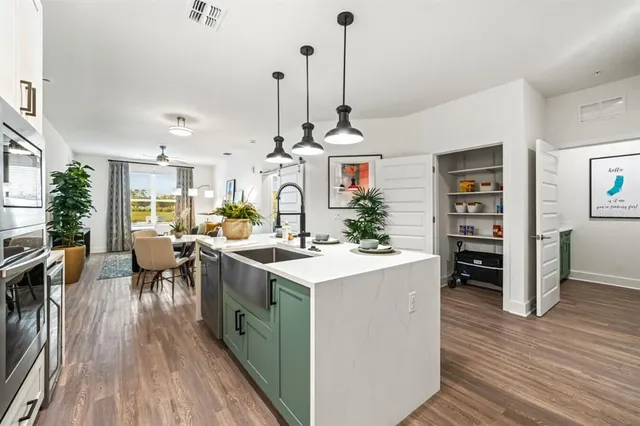 a kitchen with stainless steel appliances a sink a potted plant and a refrigerator