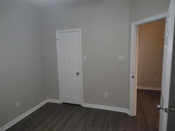 a view of an empty room with wooden floor and closet