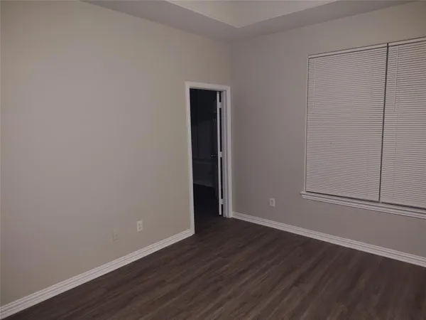 a view of an empty room with wooden floor and closet