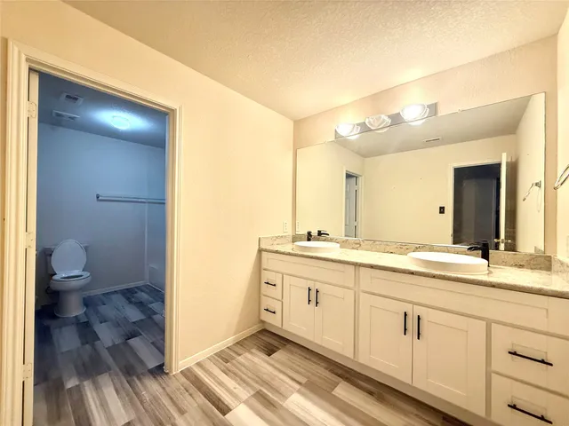 a spacious bathroom with a granite countertop sink a toilet and a shower