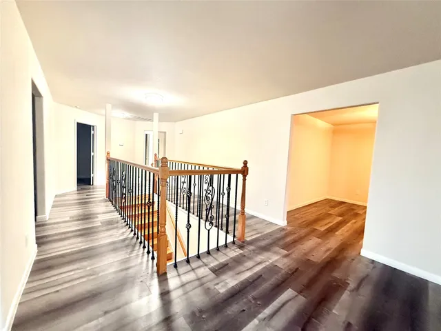 a view of a hallway with wooden floor and staircase