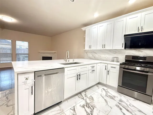 a kitchen with granite countertop a sink a stove and cabinets