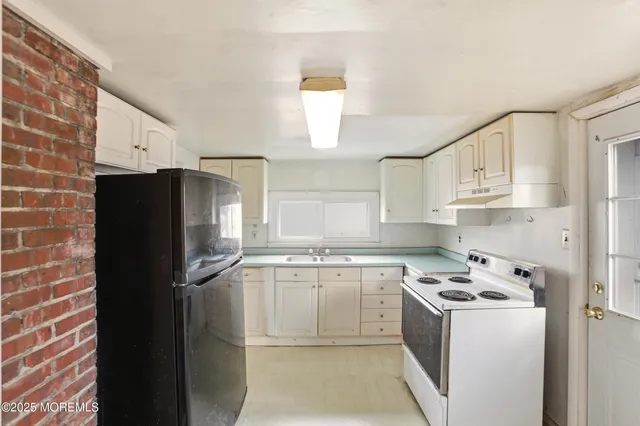 a kitchen with stainless steel appliances a refrigerator a sink and white cabinets