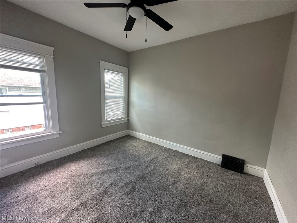10820 Bellaire Road Cleveland, OH 44111 - Photo 10 of 24 Spare room featuring dark carpet, plenty of natural light, and ceiling fan