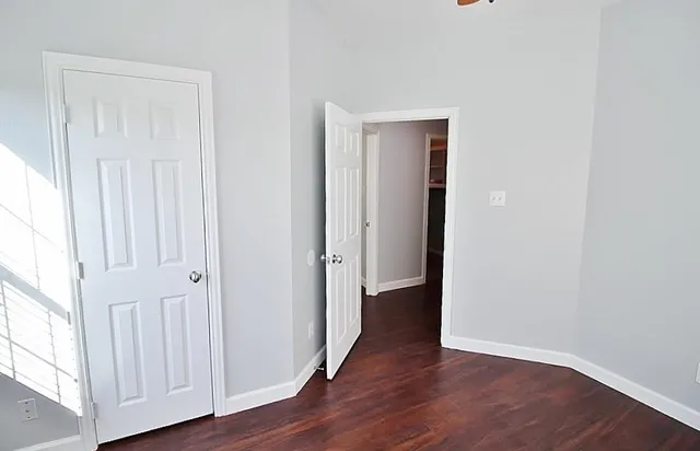 an empty room with wooden floor & windows
