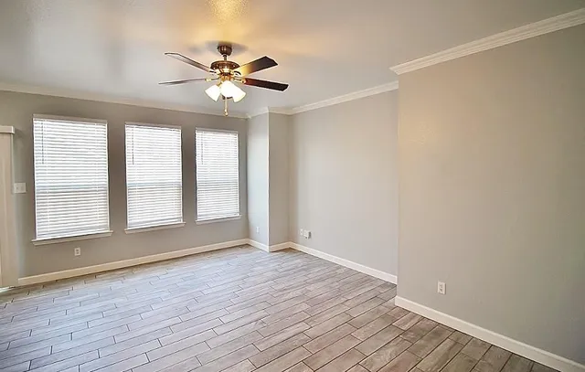 a view of an empty room with wooden floor and a window