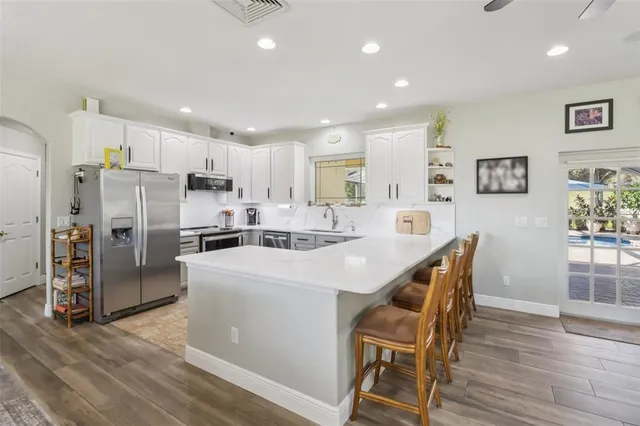 a kitchen with stainless steel appliances a refrigerator a stove a sink dishwasher and a dining table with wooden floor