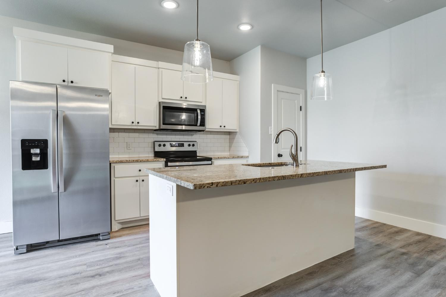 2528 137th Street Lubbock, TX 79423 - Photo 8 of 35 a kitchen with stainless steel appliances a refrigerator a sink a stove a microwave and wooden floor