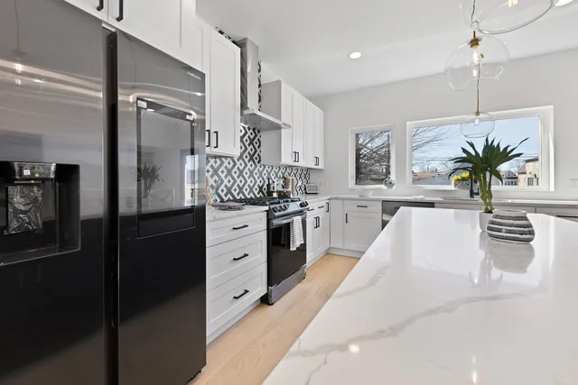a kitchen with stainless steel appliances kitchen island granite countertop a refrigerator a sink dishwasher and white cabinets with wooden floor
