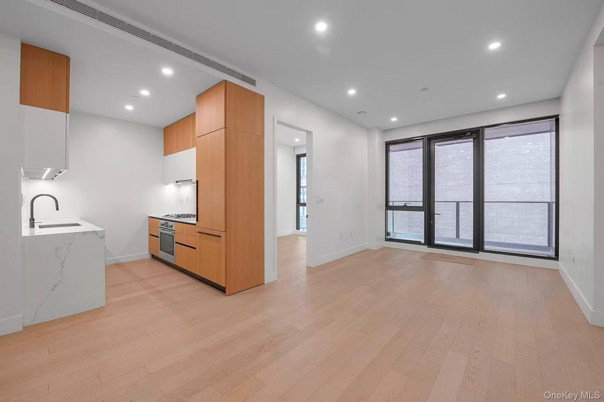 5 Ct Square West, Unit 6A Queens, NY 11101 - Photo 15 of 16 Kitchen featuring modern cabinets, light stone countertops, light wood-style flooring, recessed lighting, and open floor plan