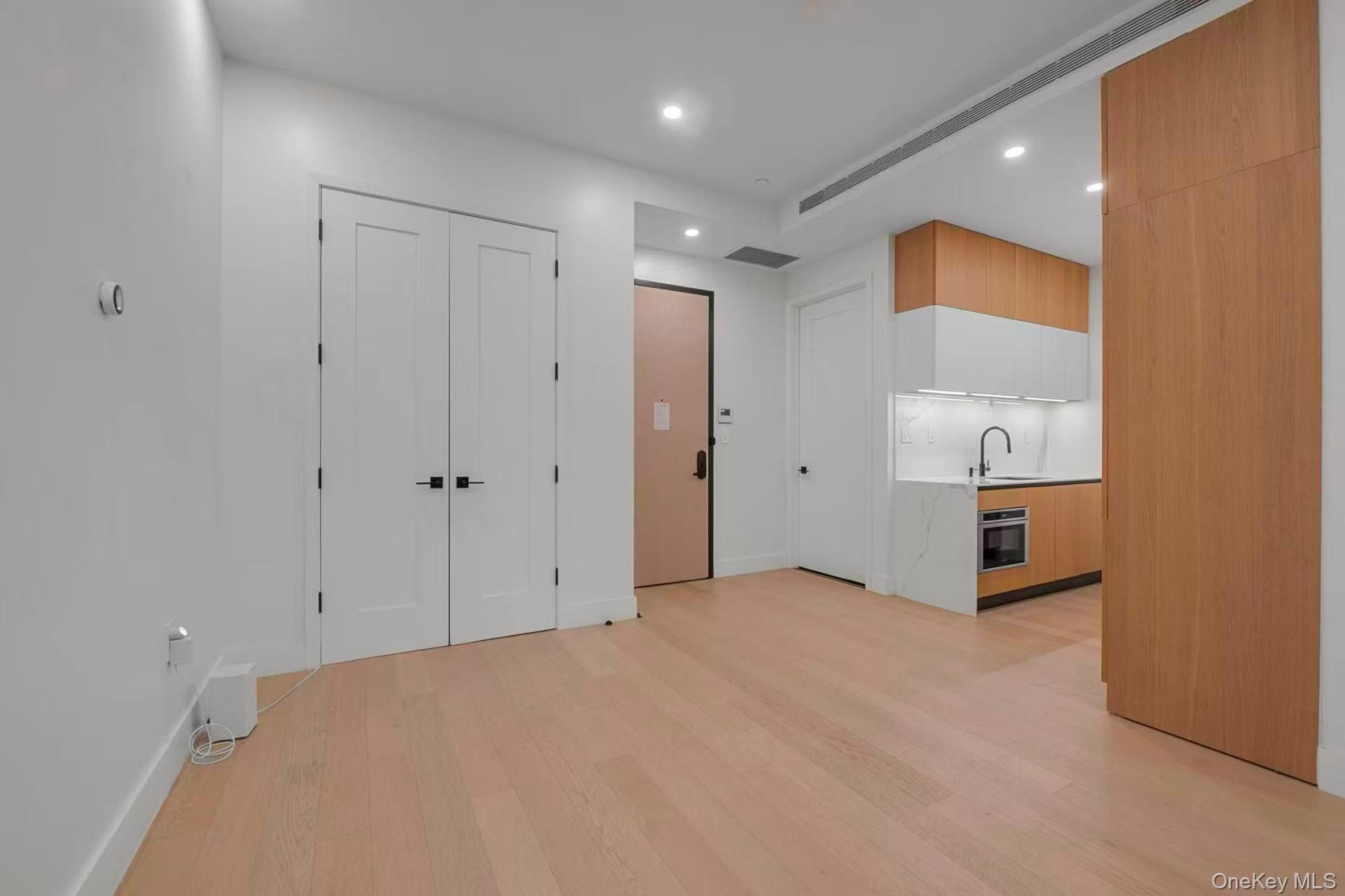 5 Ct Square West, Unit 6A Queens, NY 11101 - Photo 7 of 16 Kitchen featuring modern cabinets, light wood finished floors, stainless steel oven, recessed lighting, and white cabinets