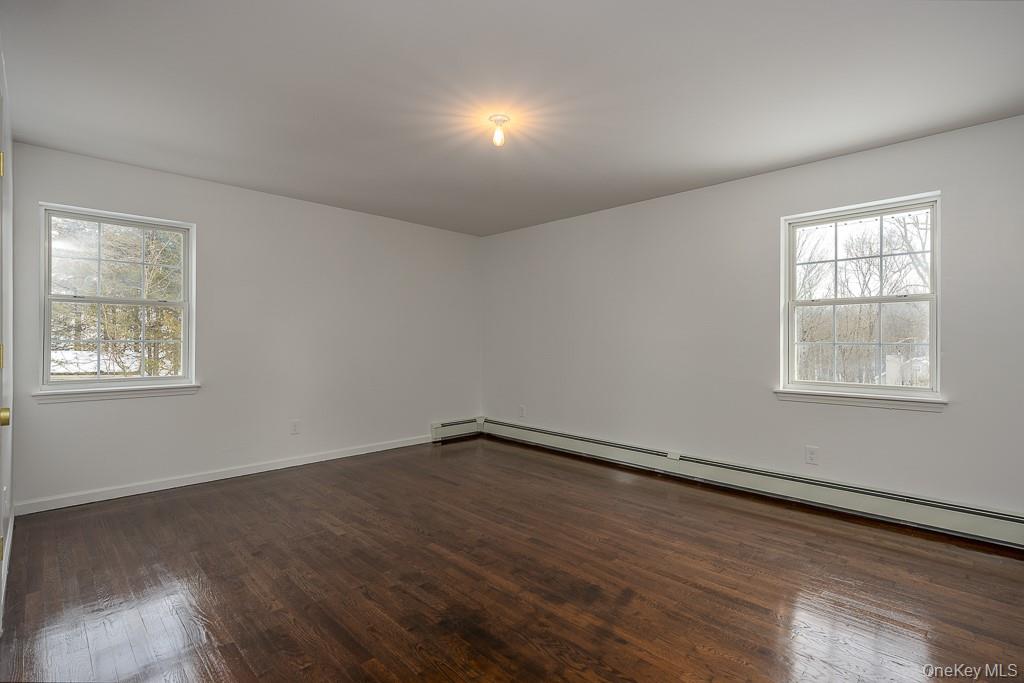 600 Twin Arch Road Rock Tavern, NY 12575 - Photo 14 of 25 Unfurnished room featuring a baseboard heating unit, dark wood-style floors, and plenty of natural light