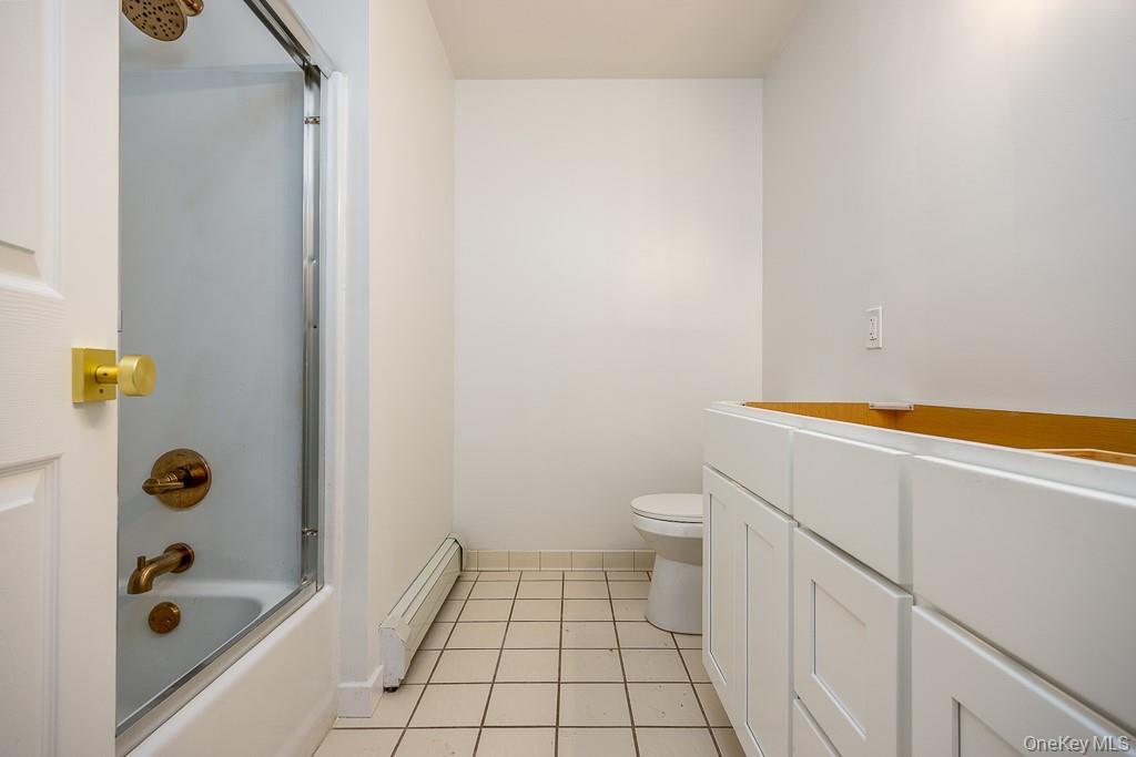 600 Twin Arch Road Rock Tavern, NY 12575 - Photo 16 of 25 Bathroom with combined bath / shower with glass door, a baseboard radiator, vanity, and light tile patterned floors