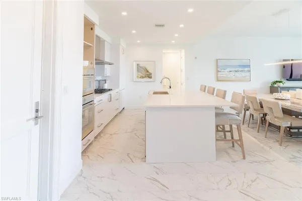 a large white kitchen with a table and chairs