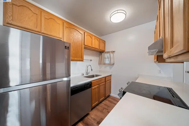 a kitchen with stainless steel appliances granite countertop a refrigerator a sink and a stove with wooden floor
