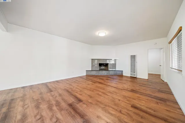 a view of empty room with wooden floor and fireplace