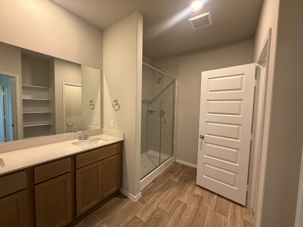 2601 Foss Road Manor, TX 78653 - Photo 19 of 40 Wood-look flooring complements the spacious vanity and modern glass shower enclosure in this bathroom.