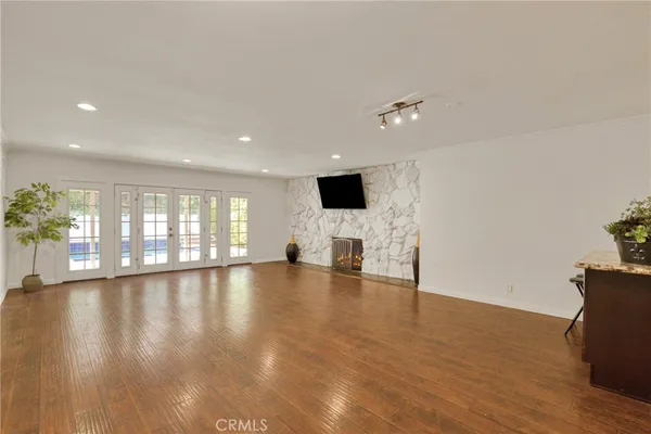 a view of an empty room with window and wooden floor