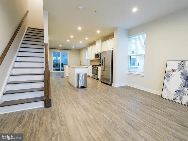 a view of a kitchen with wooden floor electronic appliances and stairs