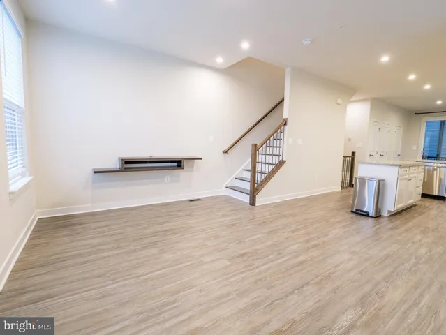 a view of an empty room with wooden floor and stairs