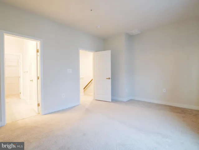 a view of a hallway with wooden floor and a bathroom