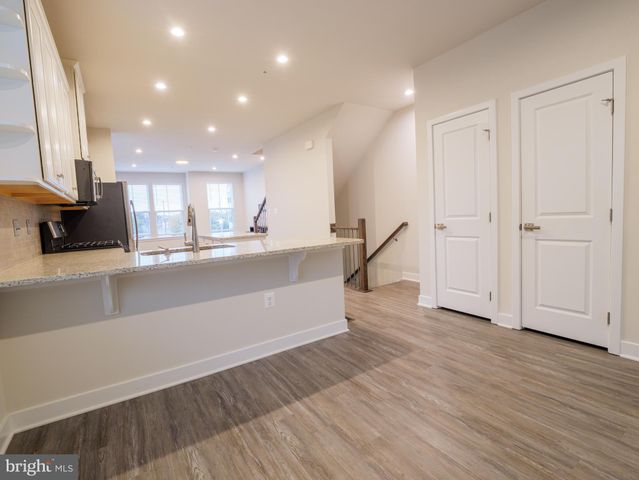 a large kitchen with stainless steel appliances a large counter top and a wooden floor