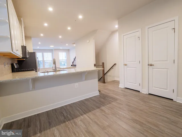 a large kitchen with stainless steel appliances a large counter top and a wooden floor