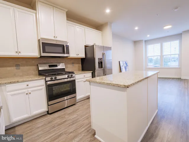 a kitchen with stainless steel appliances kitchen island granite countertop a stove a sink and a refrigerator
