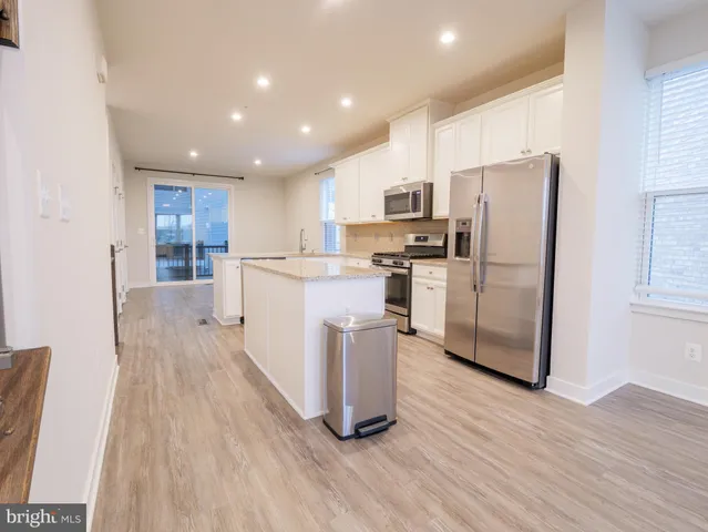a kitchen with stainless steel appliances a refrigerator a stove top oven and wooden floors
