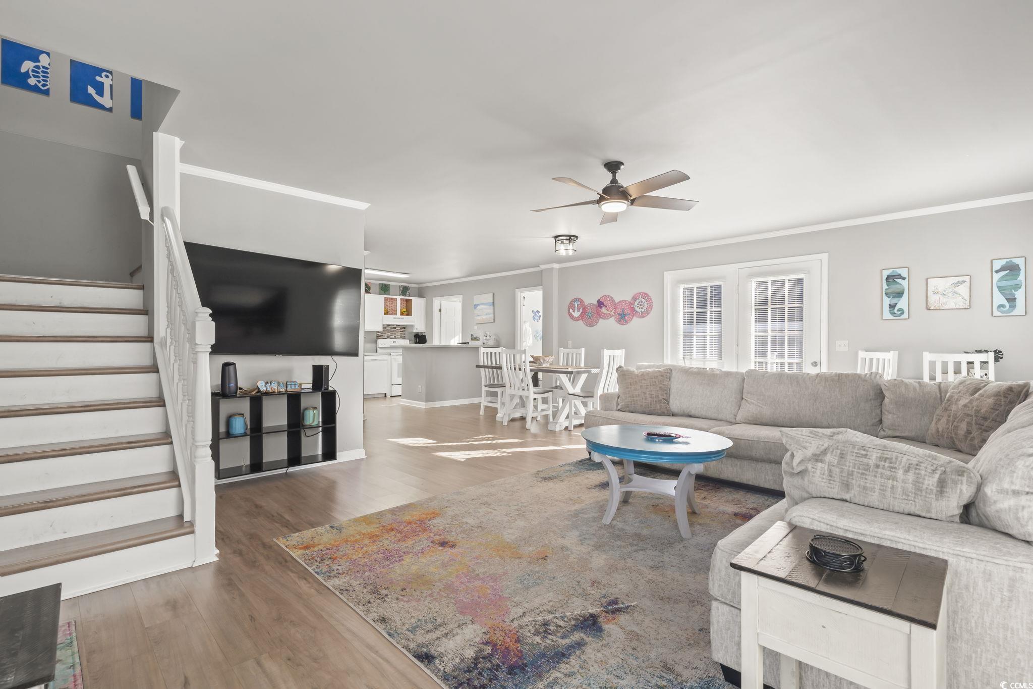 409 Knoll Court Myrtle Beach, SC 29588 - Photo 12 of 33 Living room with stairs, wood finished floors, a ceiling fan, and crown molding