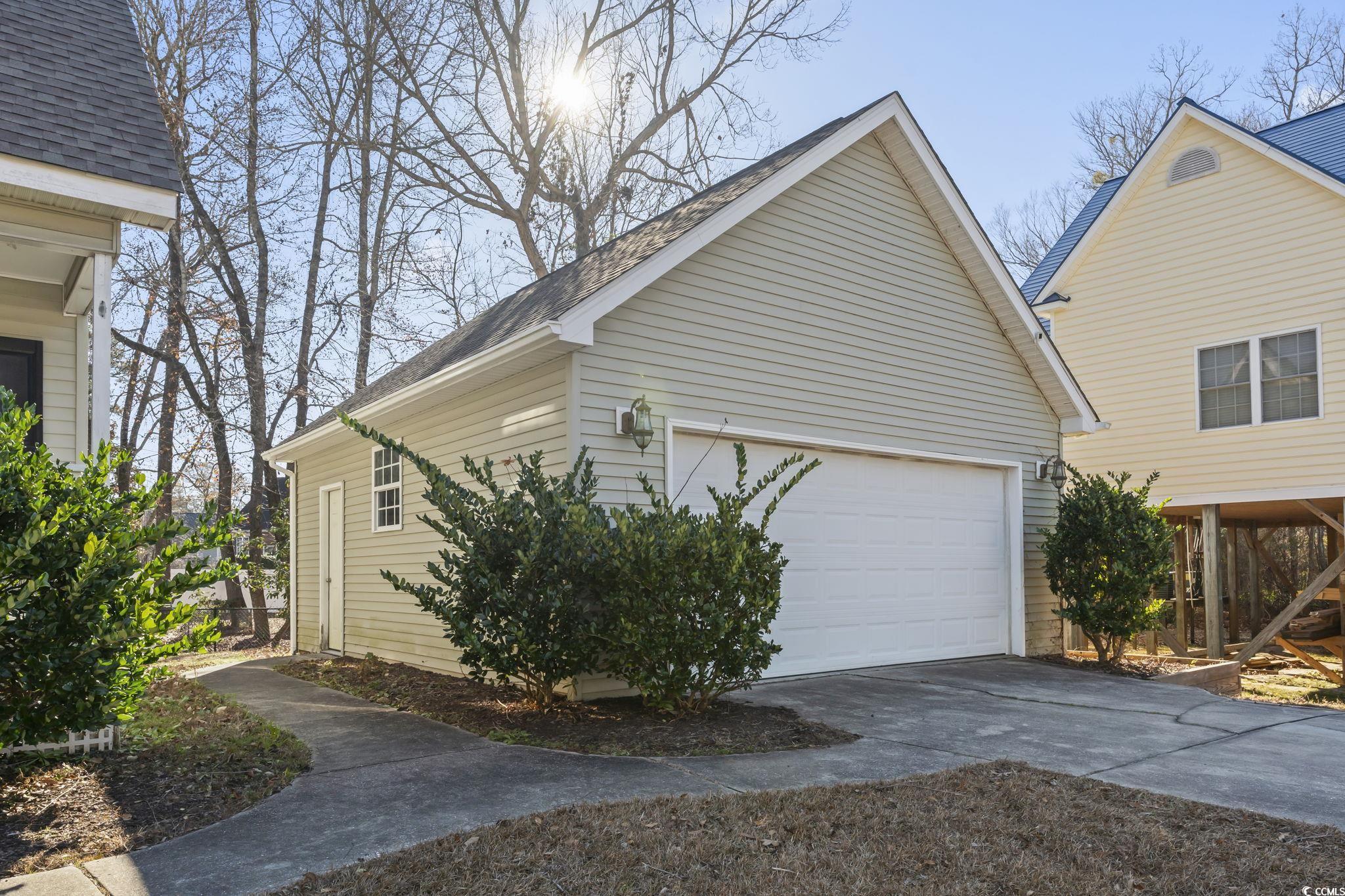409 Knoll Court Myrtle Beach, SC 29588 - Photo 5 of 33 View of property exterior featuring a garage, an outdoor structure, concrete driveway, and roof with shingles
