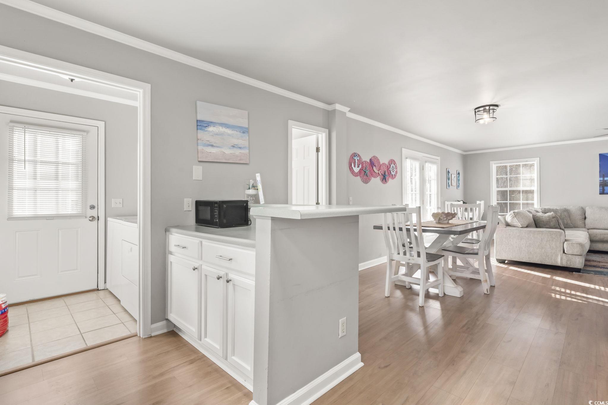 409 Knoll Court Myrtle Beach, SC 29588 - Photo 33 of 33 Kitchen with white cabinetry, open floor plan, light countertops, crown molding, and light wood finished floors