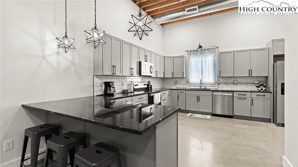 a kitchen with stainless steel appliances granite countertop a stove a sink and a microwave