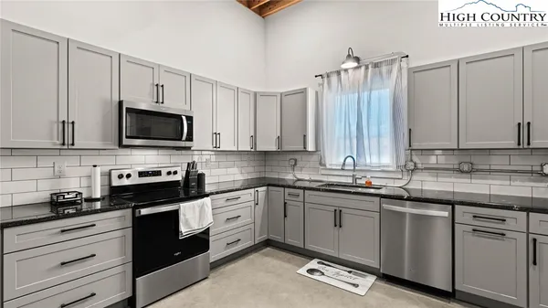 a kitchen with stainless steel appliances kitchen island granite countertop a refrigerator a stove a sink a dining table and chairs with wooden floor