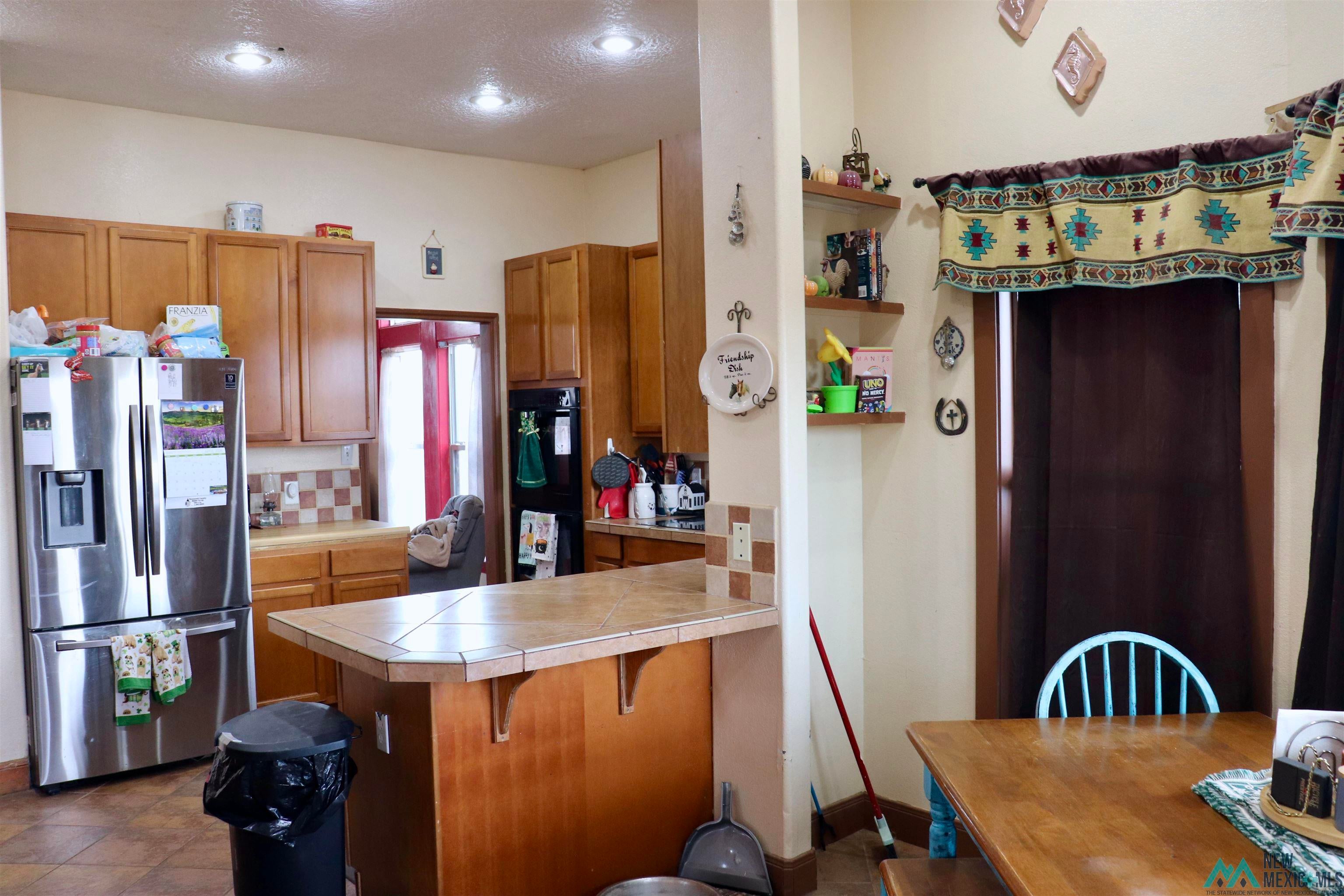 845 South Roosevelt Road South Portales, NM 88130 - Photo 13 of 47 Kitchen with a peninsula, wood finish cabinetry, stainless steel refrigerator with ice dispenser, a breakfast bar, and backsplash
