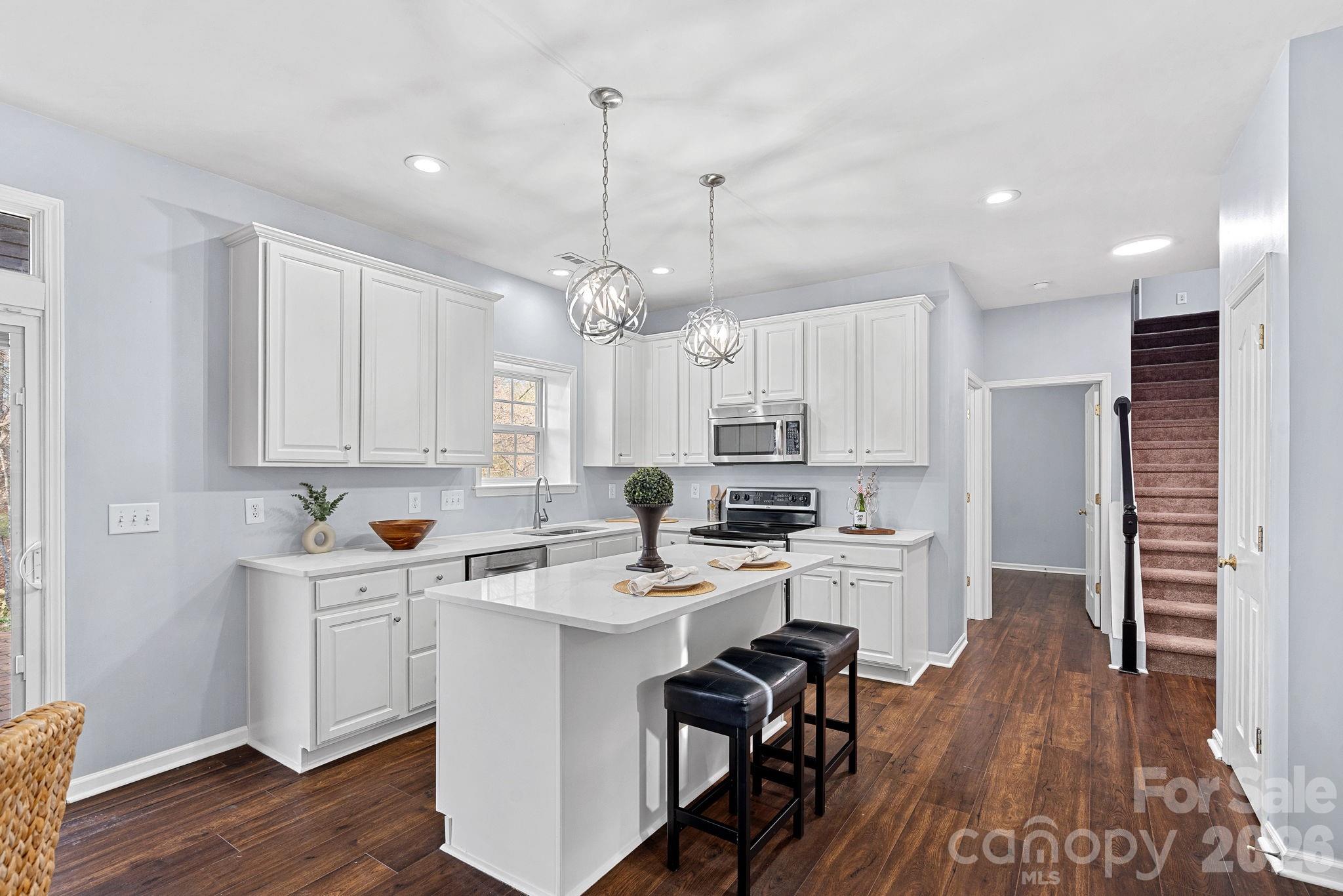 2017 East Foxwood Court Fort Mill, SC 29707 - Photo 7 of 33 a kitchen with a sink a stove a refrigerator and white cabinets with wooden floor