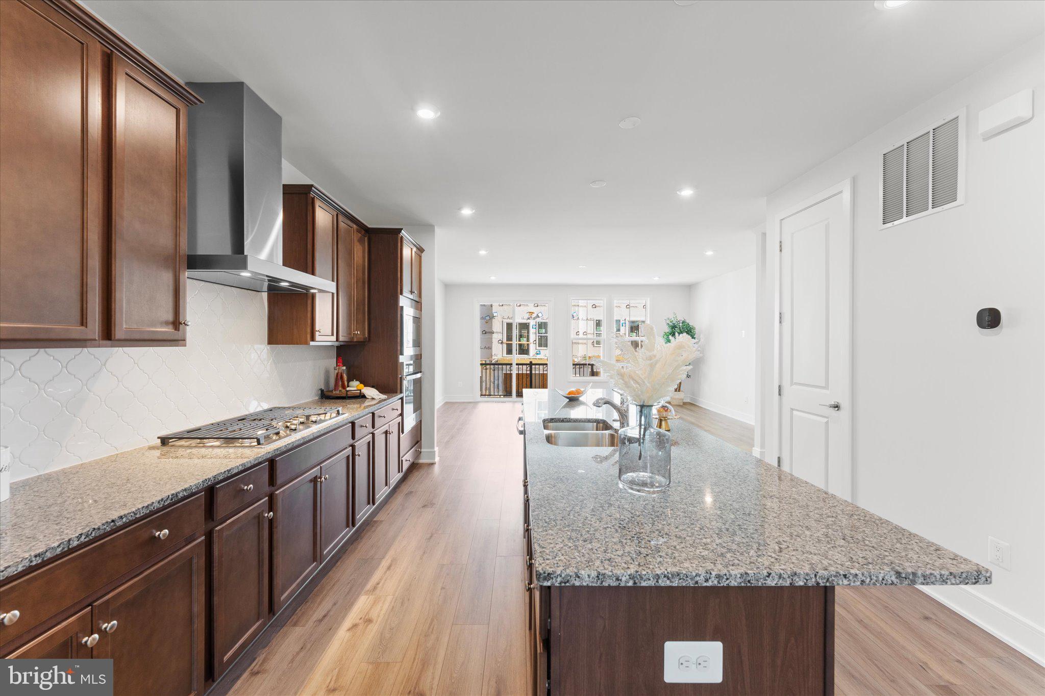 23080 Soaring Hts Terrace Ashburn, VA 20148 - Photo 12 of 44 a kitchen with stainless steel appliances granite countertop a stove top oven a sink dishwasher and cabinets with wooden floor