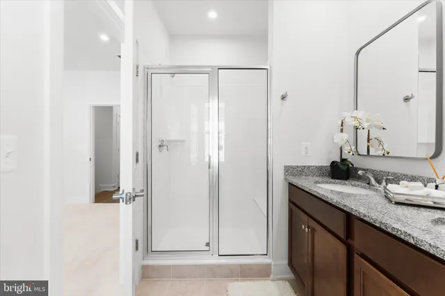 a bathroom with a granite countertop sink a mirror and shower