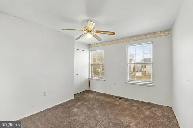 an empty room with windows and fan