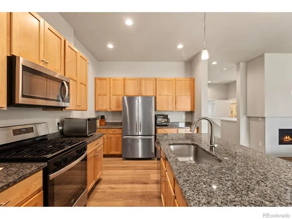 a kitchen with stainless steel appliances granite countertop a refrigerator a stove a sink a dining table and chairs