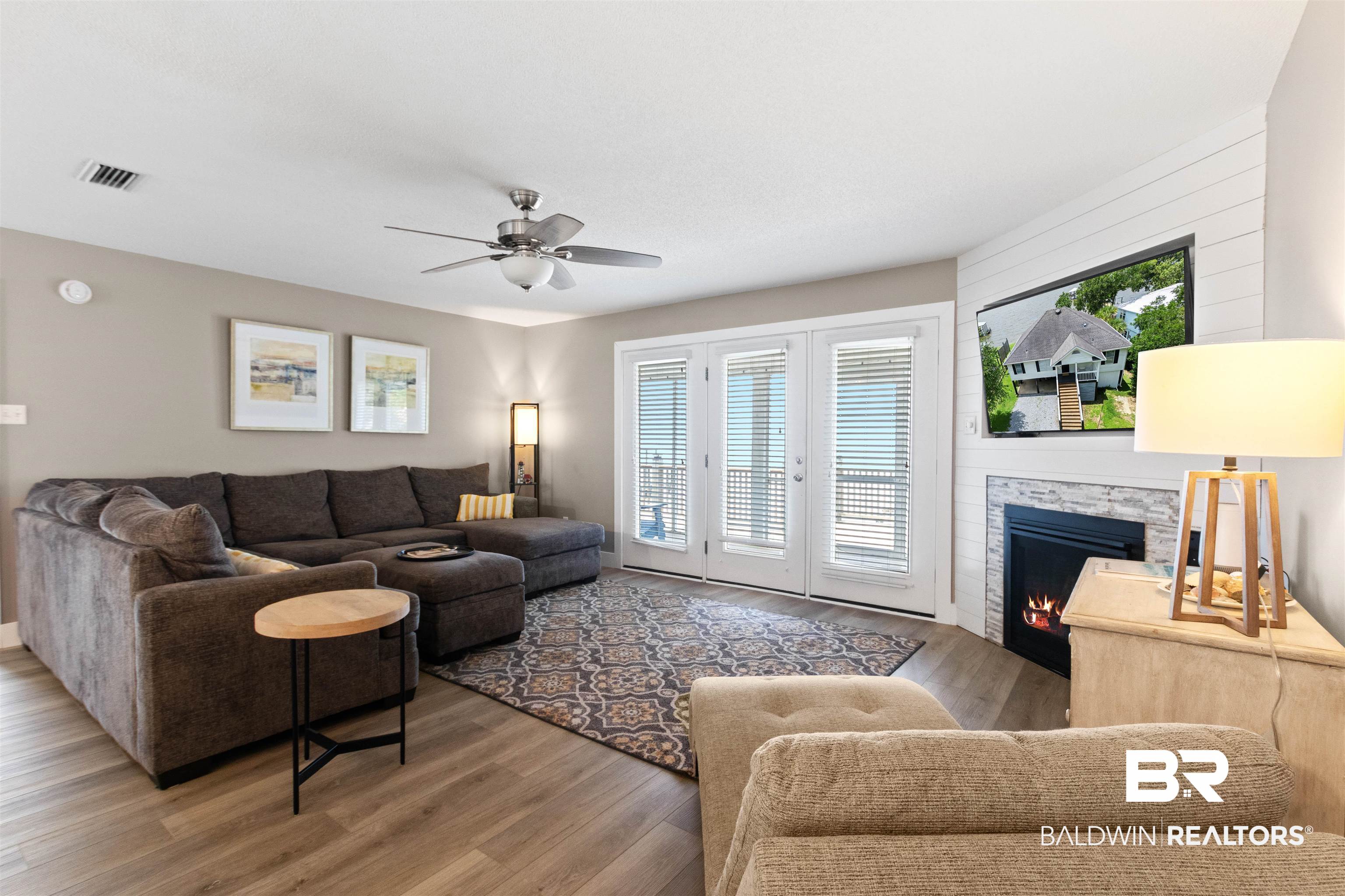 9581 South Bay Street Foley, AL 36535 - Photo 12 of 44 Living area featuring wood-finish flooring, a contemporary fireplace with stone surround, shiplap accent wall, and a ceiling fan with integrated lighting