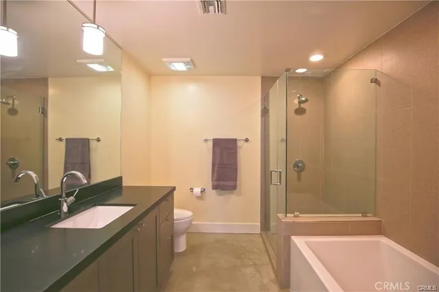 a bathroom with a granite countertop sink a toilet a mirror and shower