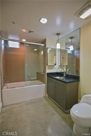 a bathroom with a granite countertop sink a toilet a mirror and bathtub