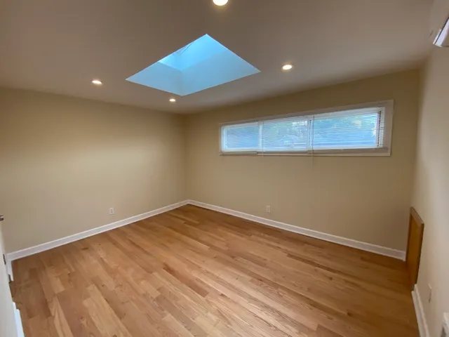 an empty room with wooden floor and fan