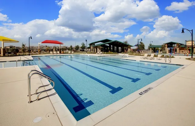 a view of swimming pool that has lawn chairs with wooden floor