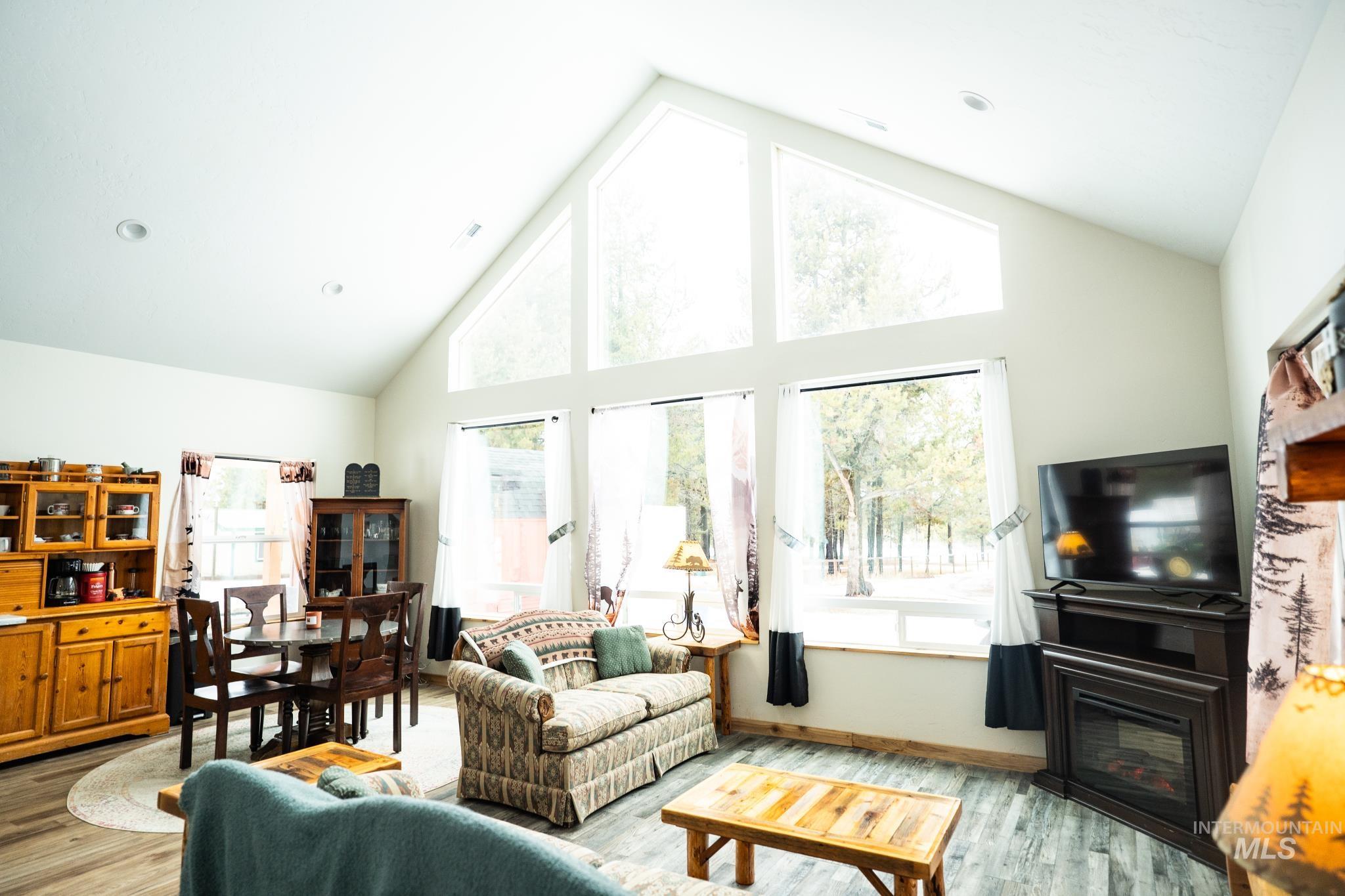 22 West Prospectors Drive Cascade, ID 83611 - Photo 27 of 29 Living room featuring high vaulted ceiling, light wood-type flooring, and a glass covered fireplace