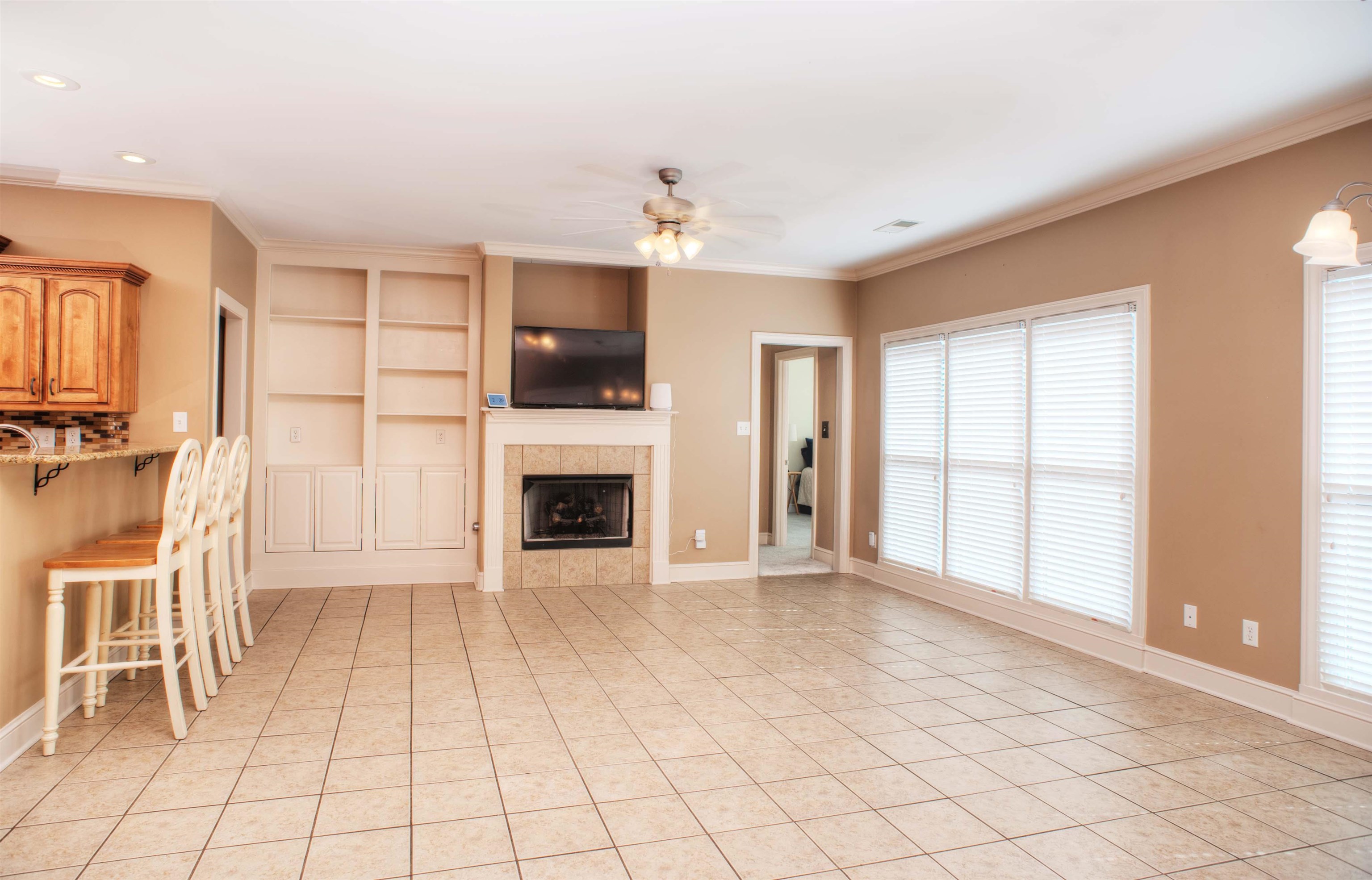 495 Tribal Woods Road Collierville, TN 38017 - Photo 9 of 22 20x17 Hearth Room with 2nd Fireplace, Tile Floor, Built-In Bookshelves, and Door to Backyard.