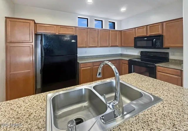 a kitchen with kitchen island a refrigerator and a sink