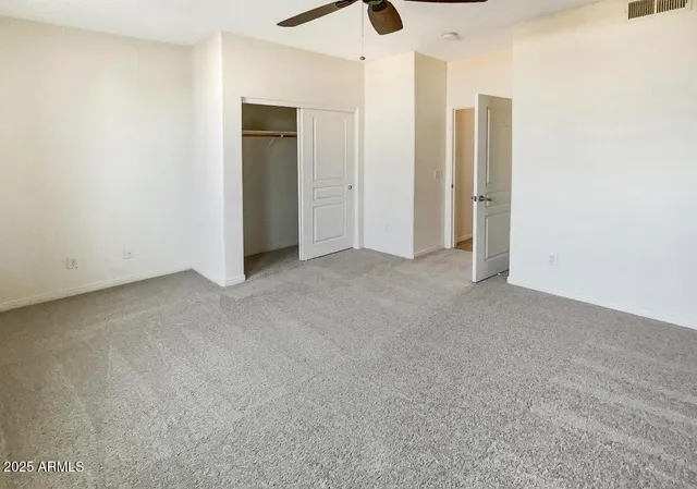 an empty room with closet and a chandelier fan